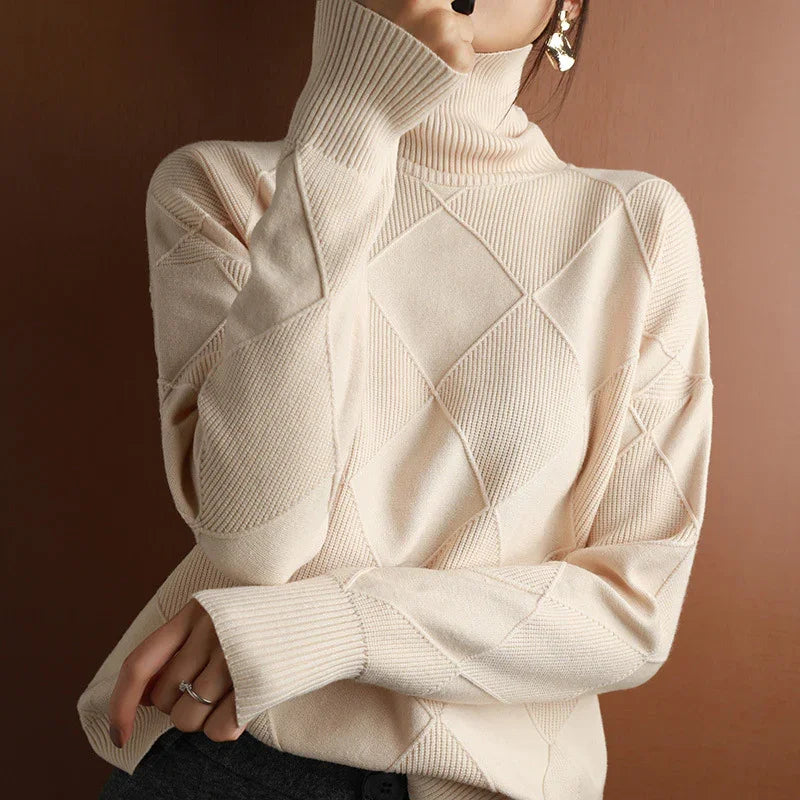 Woman wearing beige diamond-patterned turtleneck sweater with ribbed cuffs and gold earrings