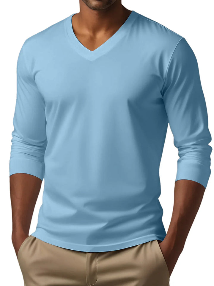 Man wearing light blue long sleeve V-neck shirt with beige pants, hands in pockets