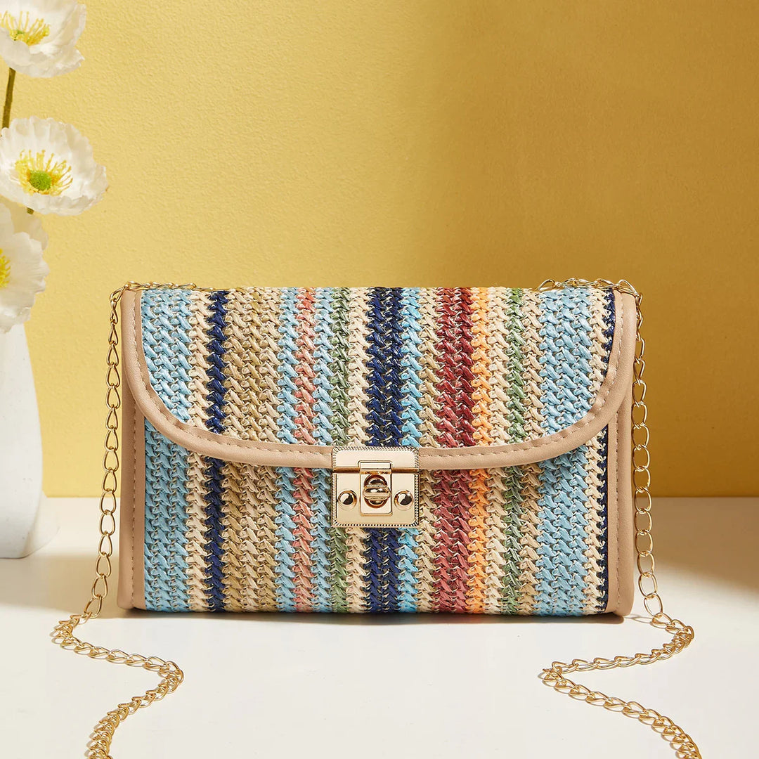 Colorful striped woven crossbody bag with gold chain strap and clasp on white table