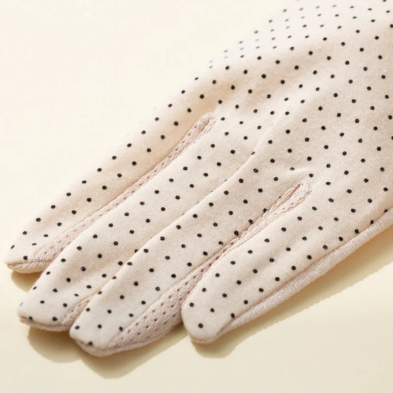 Light pink fabric gloves with black polka dots and detailed stitching on fingers