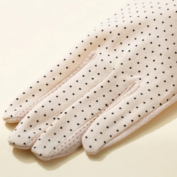 Light pink fabric gloves with black polka dots and detailed stitching on fingers