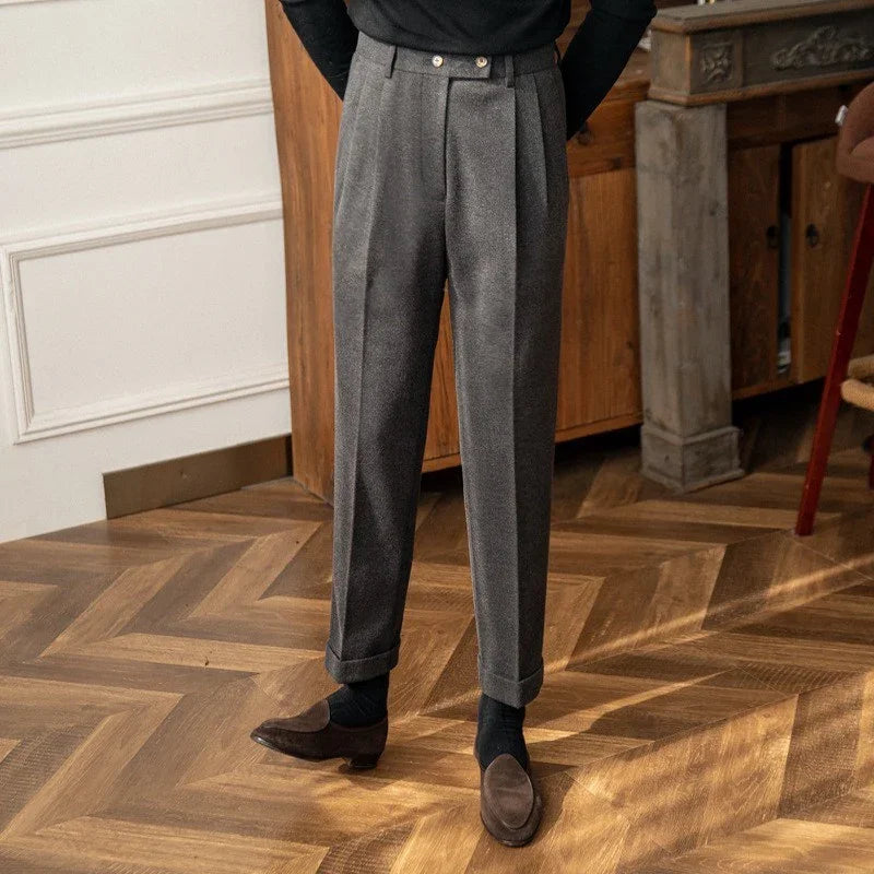 Man wearing gray tailored trousers with cuffs and brown suede loafers on wooden floor
