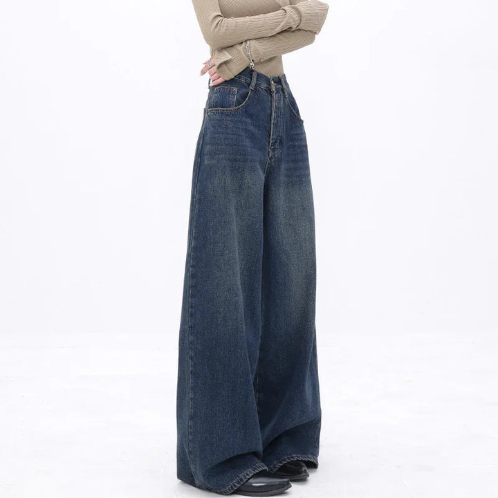Model wearing wide-leg dark blue denim jeans paired with a beige ribbed long-sleeve top on white background
