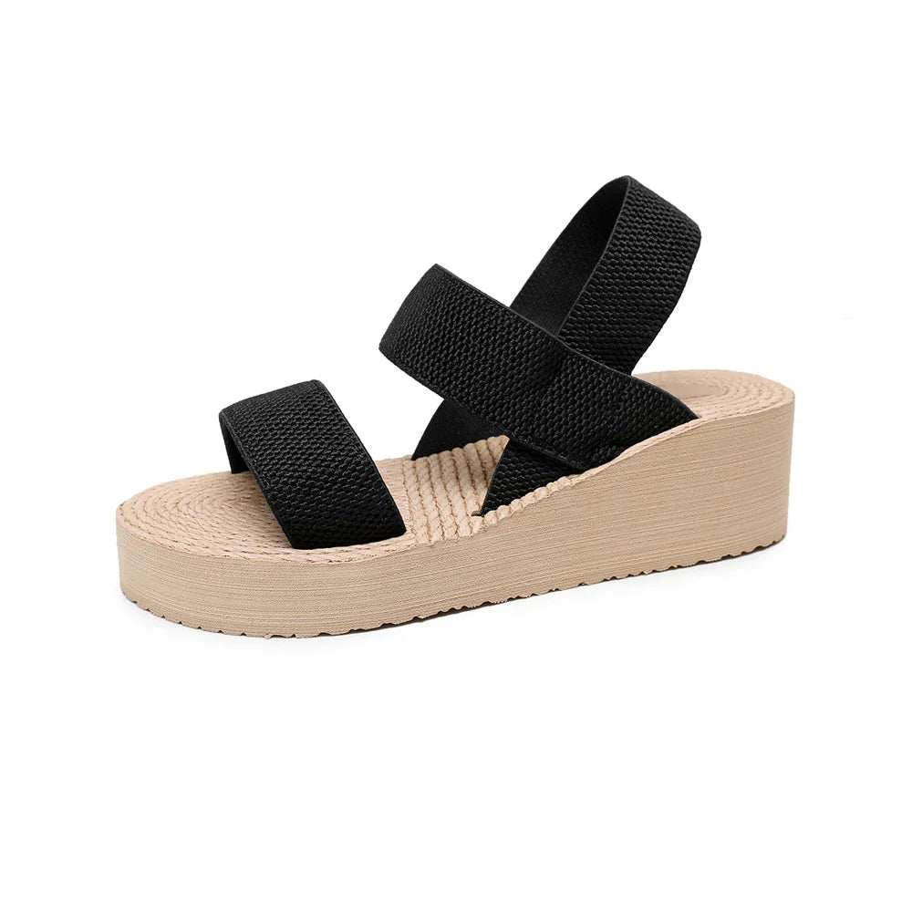 Black strap wedge sandal with beige textured platform sole on white background