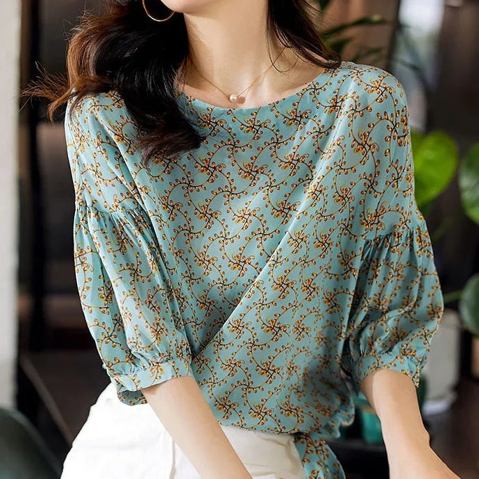 Woman wearing blue floral pattern blouse with 3/4 puff sleeves in indoor setting