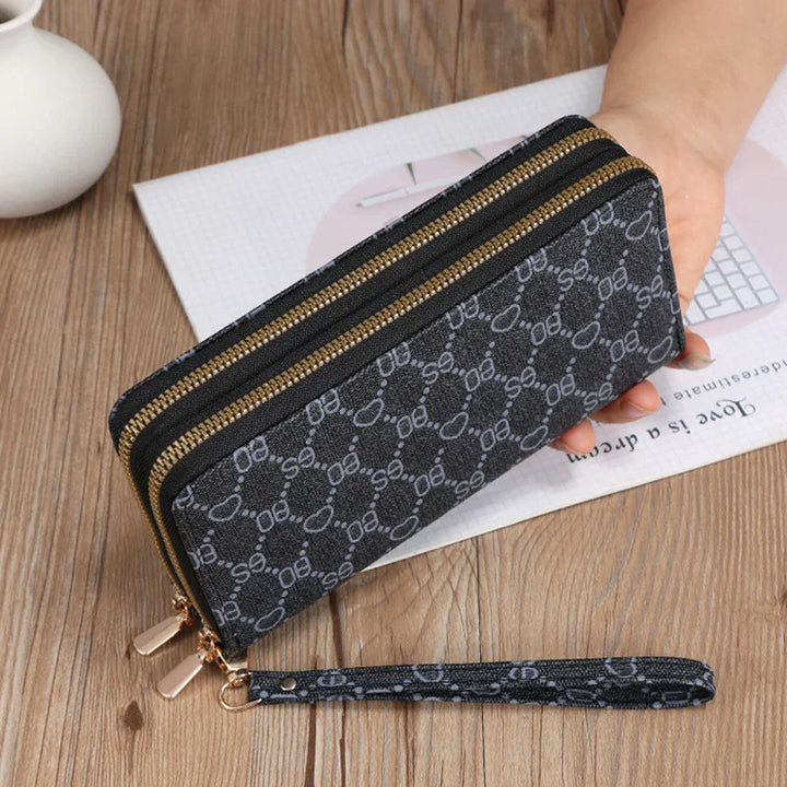 Black double zipper wallet with gray pattern and wrist strap on wooden table