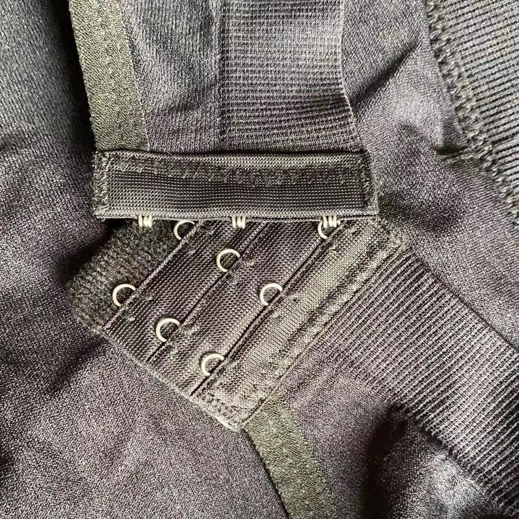 Close-up of black fabric with metal hook-and-eye closures and elastic ribbed band