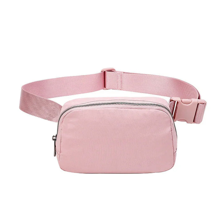 Pink fabric waist bag with silver zipper and adjustable strap on white background