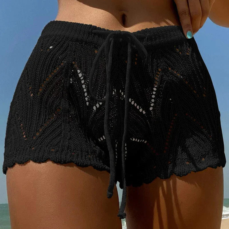 Close-up of black crochet knit beach shorts with drawstring worn by model at sunny seaside