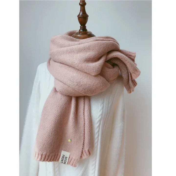 Soft pink wool scarf wrapped on wooden mannequin over white cable knit sweater