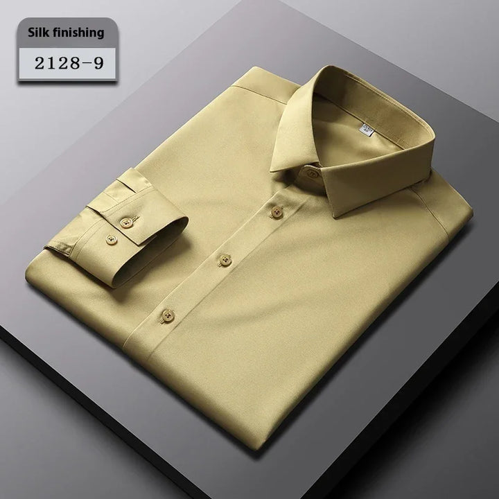 Beige folded men's dress shirt with silk finishing, buttons, and classic collar on gray surface