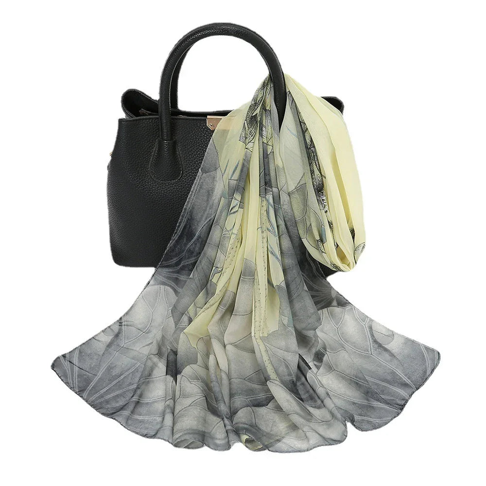 Black leather handbag with handles draped with a flowy, printed yellow and gray scarf