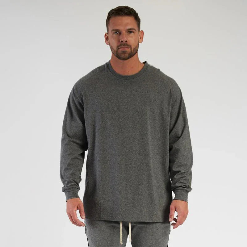 Male model wearing a long-sleeve dark gray casual sweatshirt and matching sweatpants on a white background