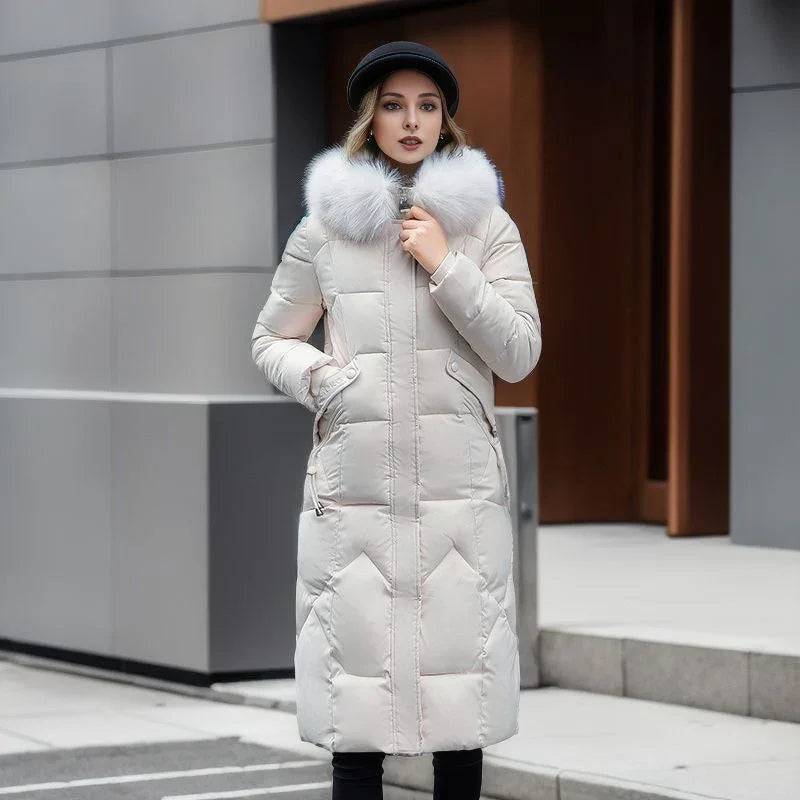 Woman in a long beige winter coat with fur collar and black hat standing outdoors