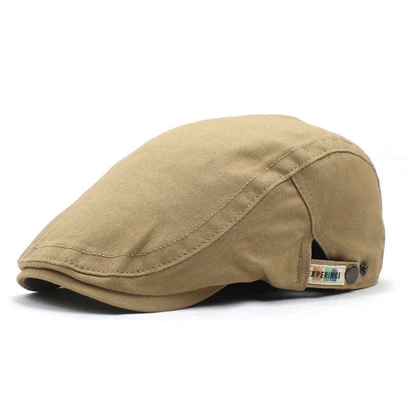 Beige flat cap with button detail and small fabric tag on side, isolated on white background