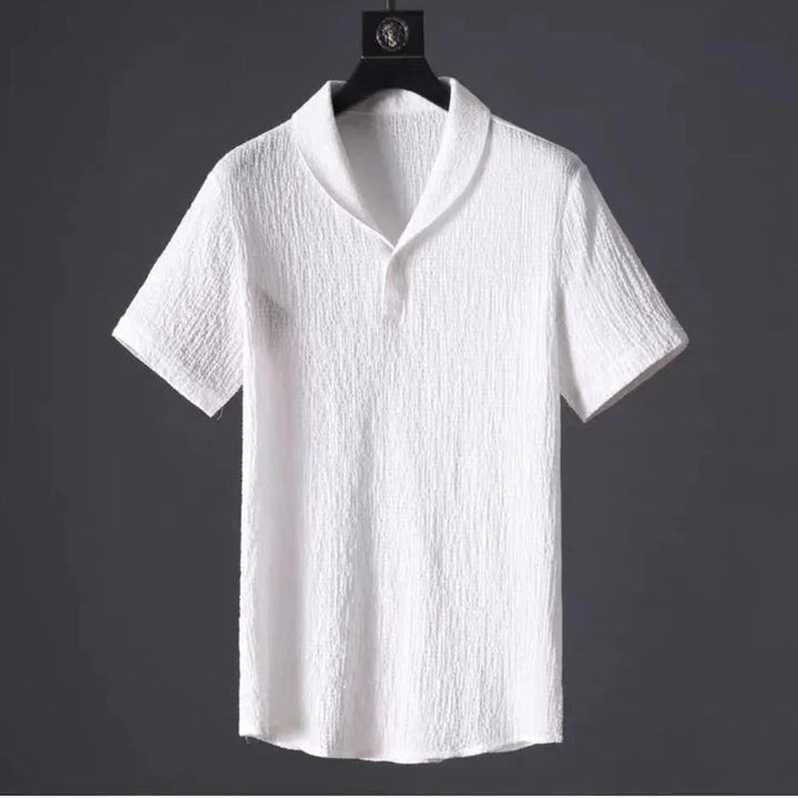 White textured short sleeve shirt with shawl collar hanging on black hanger against dark background