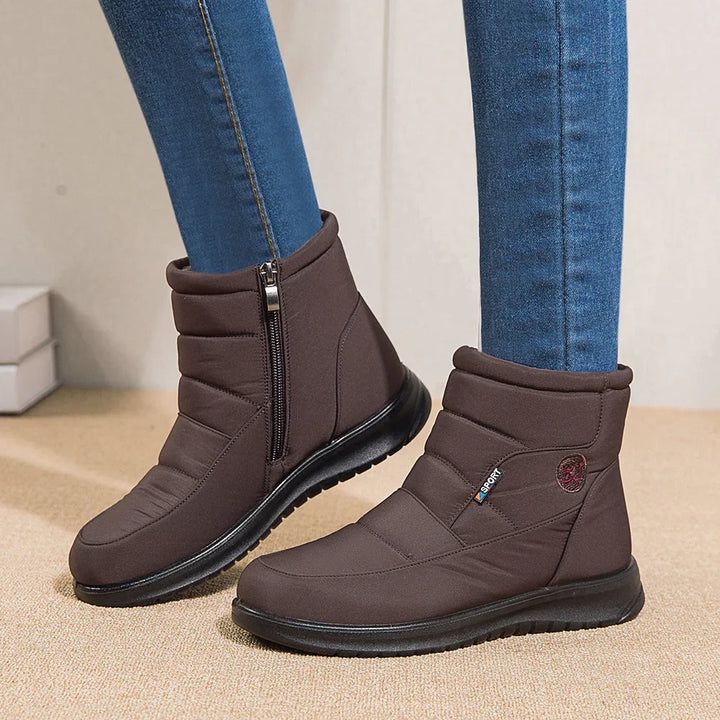 Brown winter ankle boots with side zipper and black sole worn with blue jeans on carpet