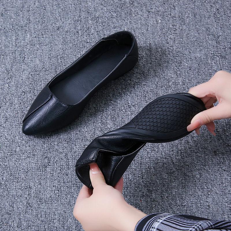 Black flexible leather flats with textured rubber sole on grey carpet