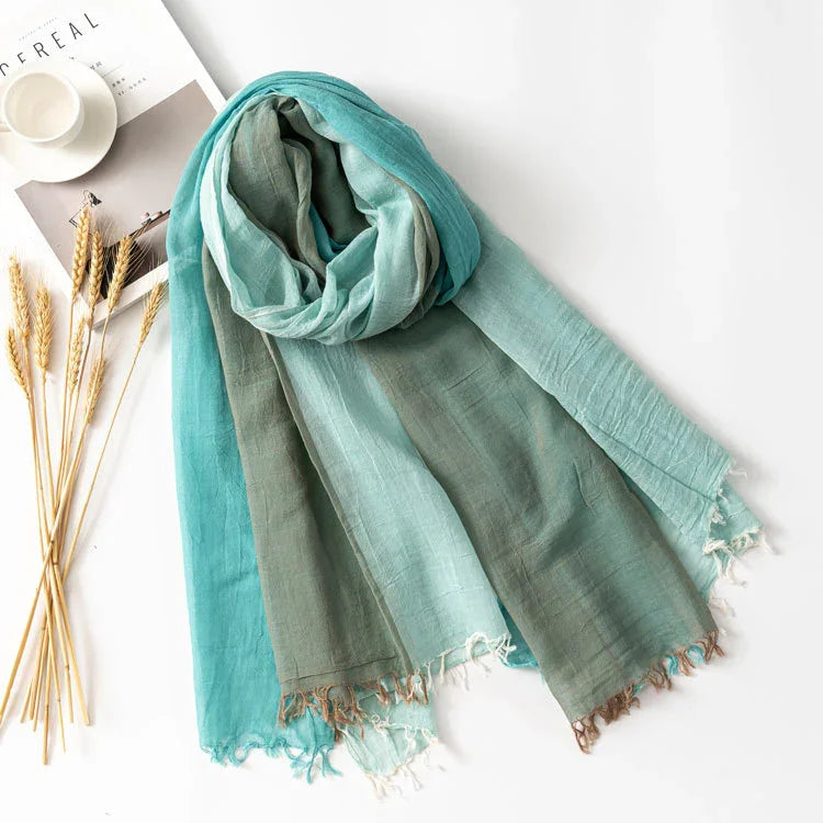 Lightweight blue and green ombre scarf with fringed edges displayed on white surface with wheat stalks and magazine