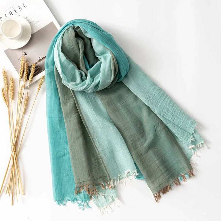 Lightweight blue and green ombre scarf with fringed edges displayed on white surface with wheat stalks and magazine