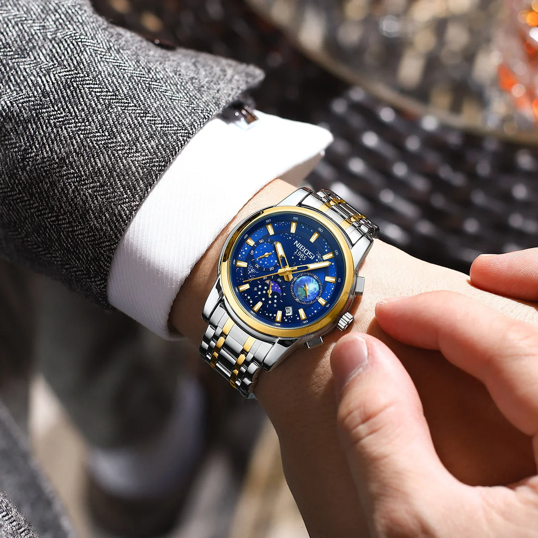 Mens luxury wristwatch with blue dial, gold accents, and silver-gold metal band on wrist