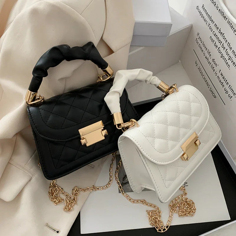 Black and white quilted leather handbags with gold chain straps and gold clasps on beige fabric