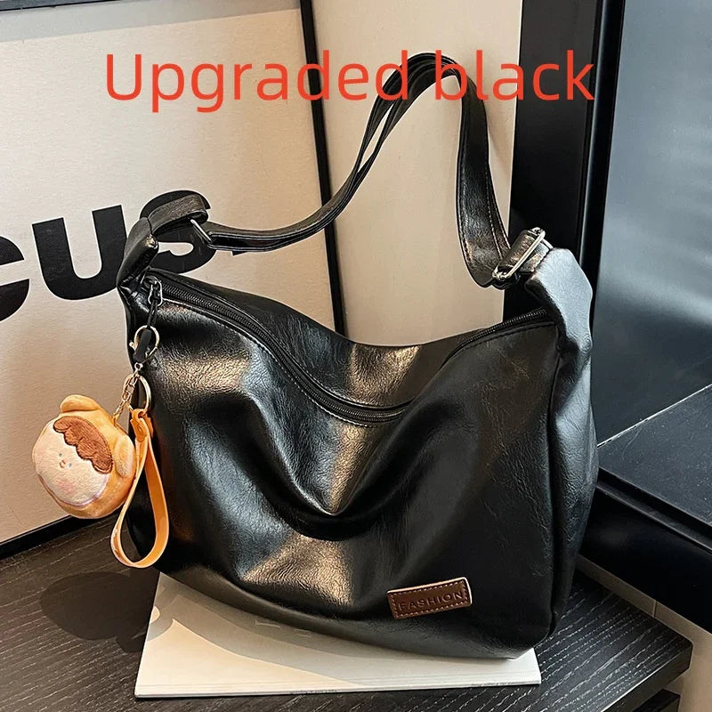 Upgraded black leather shoulder bag with zipper and brown 'Fashion' label, displayed with plush keychain