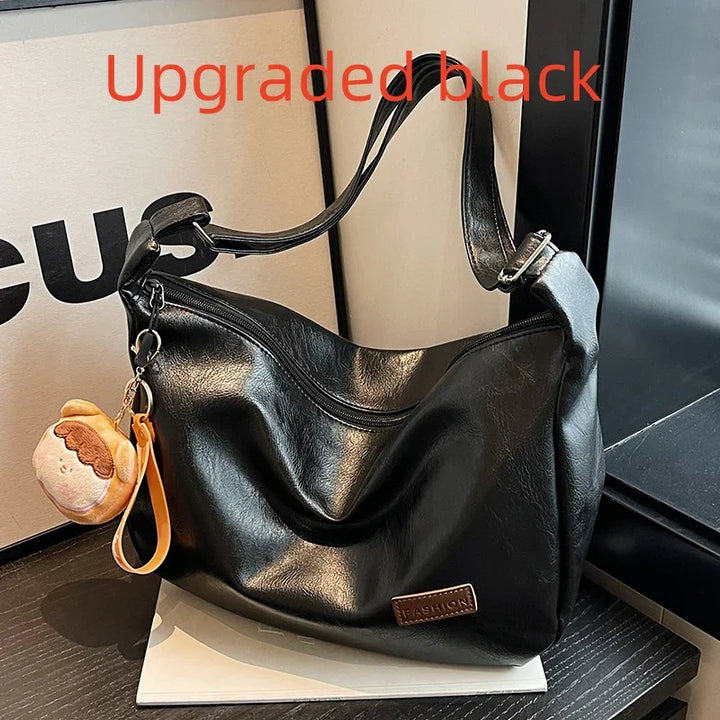 Upgraded black leather shoulder bag with zipper and brown 'Fashion' label, displayed with plush keychain