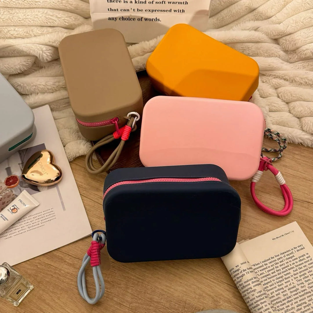 Assorted colorful rectangular travel cosmetic bags on wooden surface with magazines and soft fabric