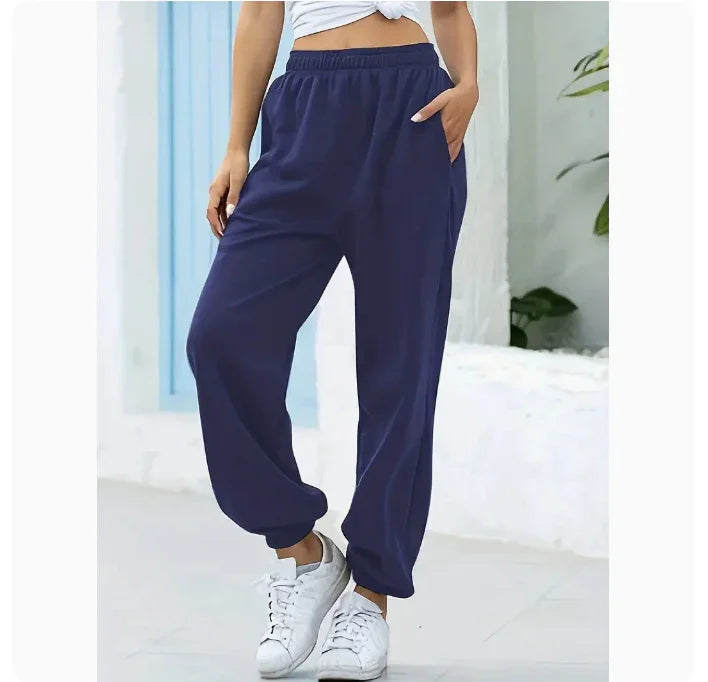 Woman wearing navy blue casual jogger pants and white sneakers in a bright indoor setting