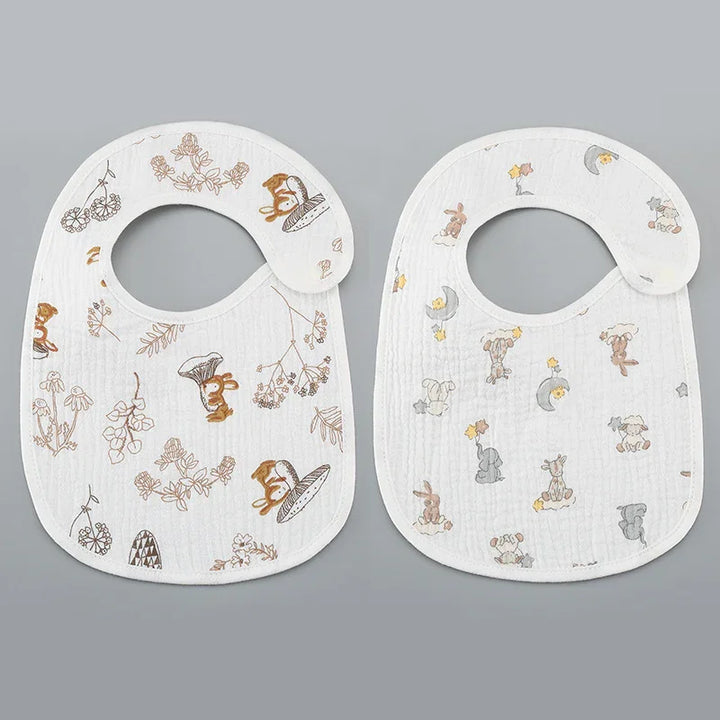 Two white baby bibs with woodland animal and floral prints on gray background