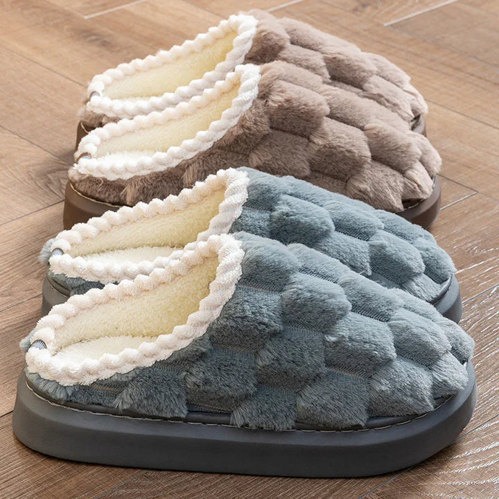 Pair of cozy plush indoor slippers with textured fabric and soft lining on wooden floor