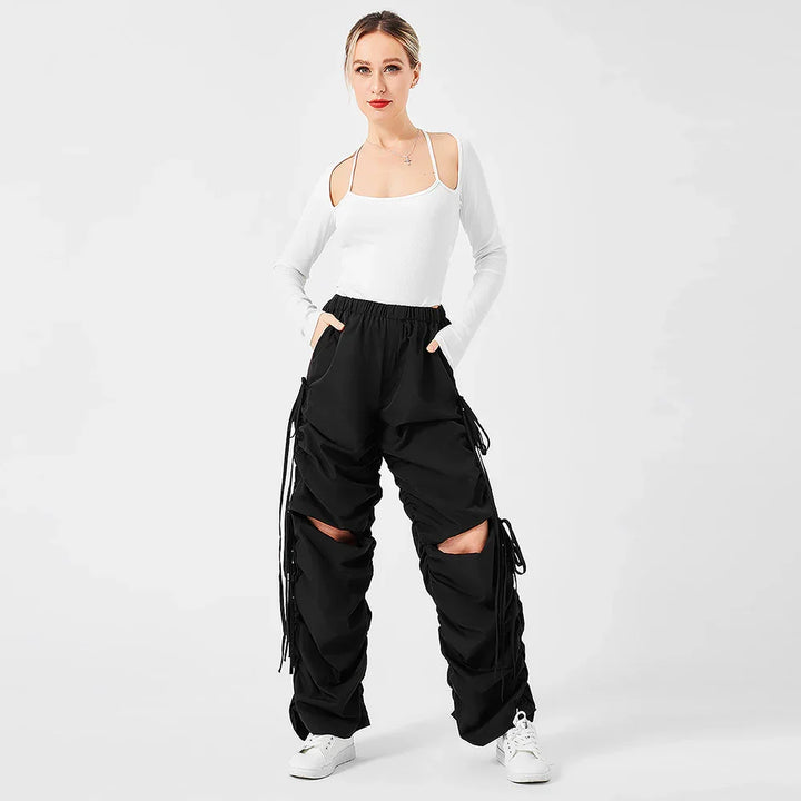 Woman wearing white cold shoulder top and black cargo pants with cut-out knees and white sneakers