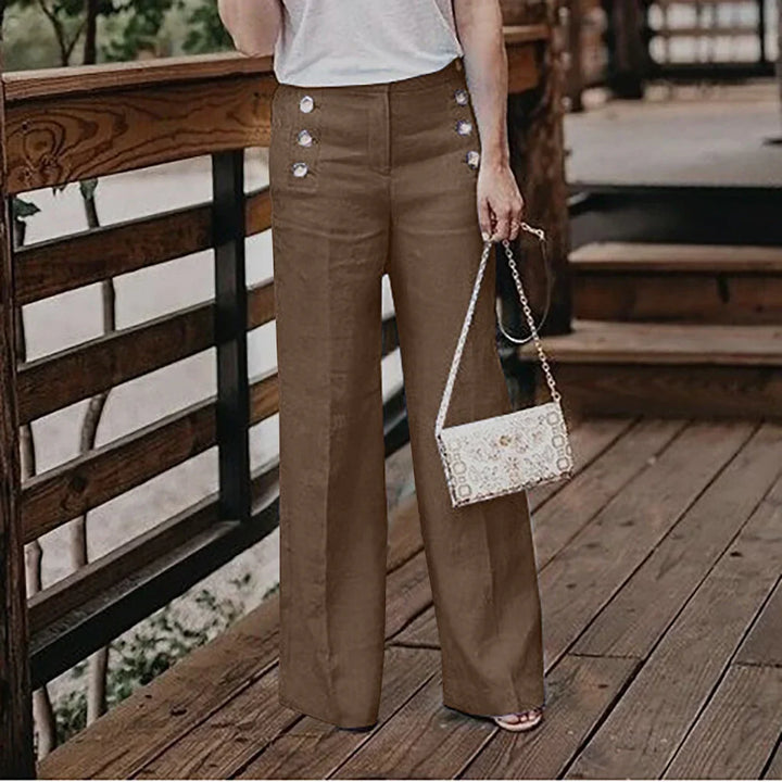 Woman wearing high-waist brown wide-leg pants with decorative buttons holding a small white purse