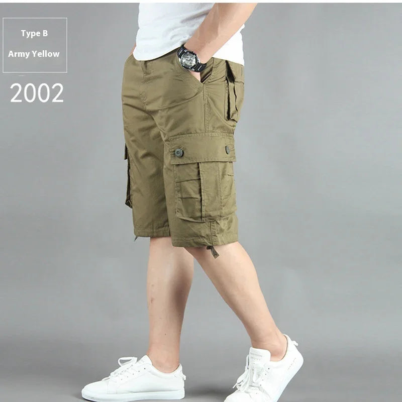 Man wearing army yellow cargo shorts with multiple pockets and white sneakers on gray background