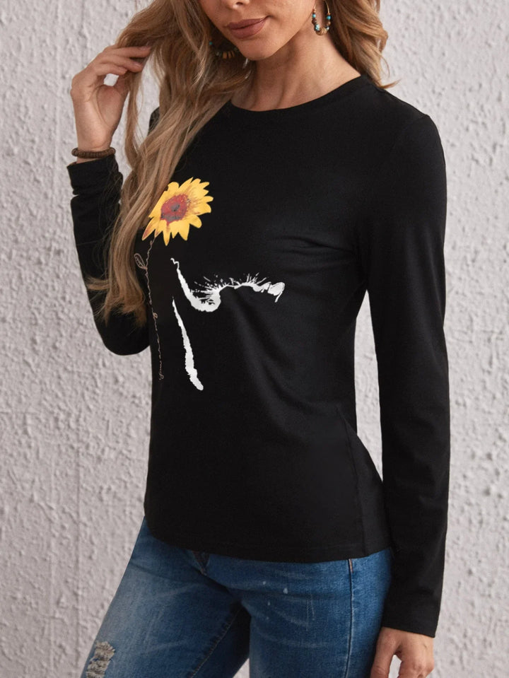 Woman wearing black long sleeve top with yellow sunflower graphic design and blue jeans