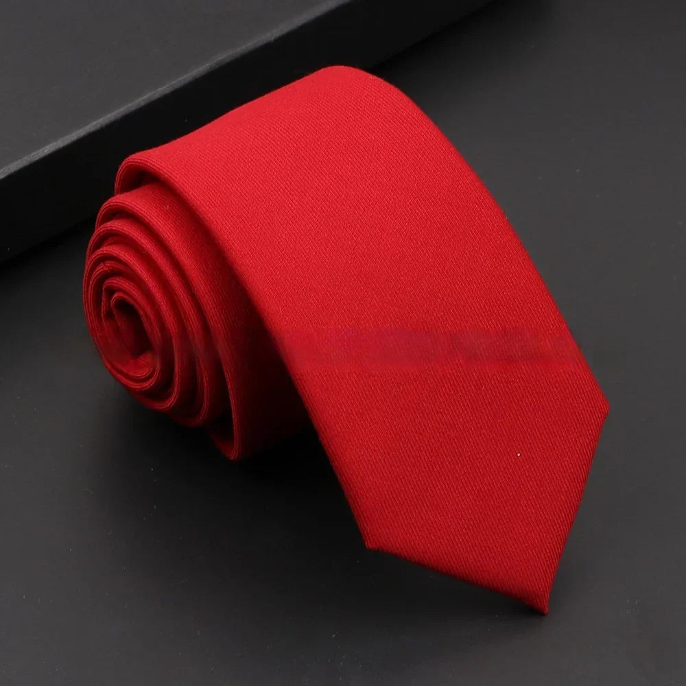 Rolled red necktie on a black surface with a black box corner visible