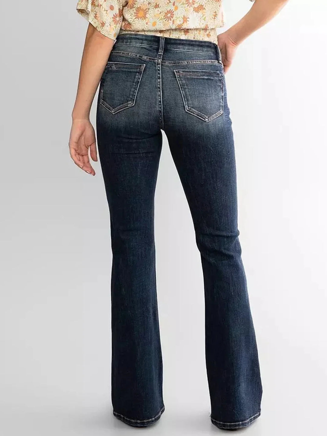 Back view of woman wearing dark blue high-waisted flared jeans with pockets
