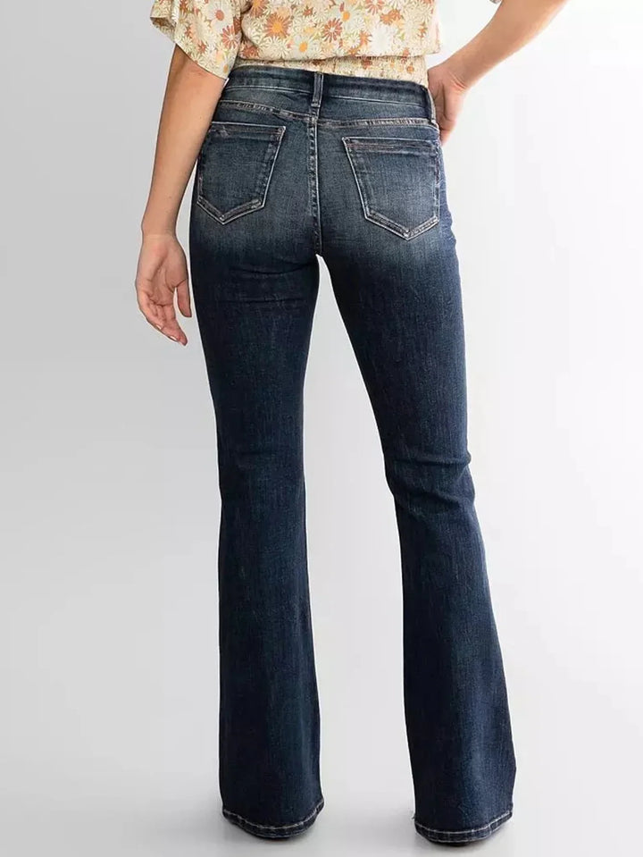 Back view of woman wearing dark blue high-waisted flared jeans with pockets