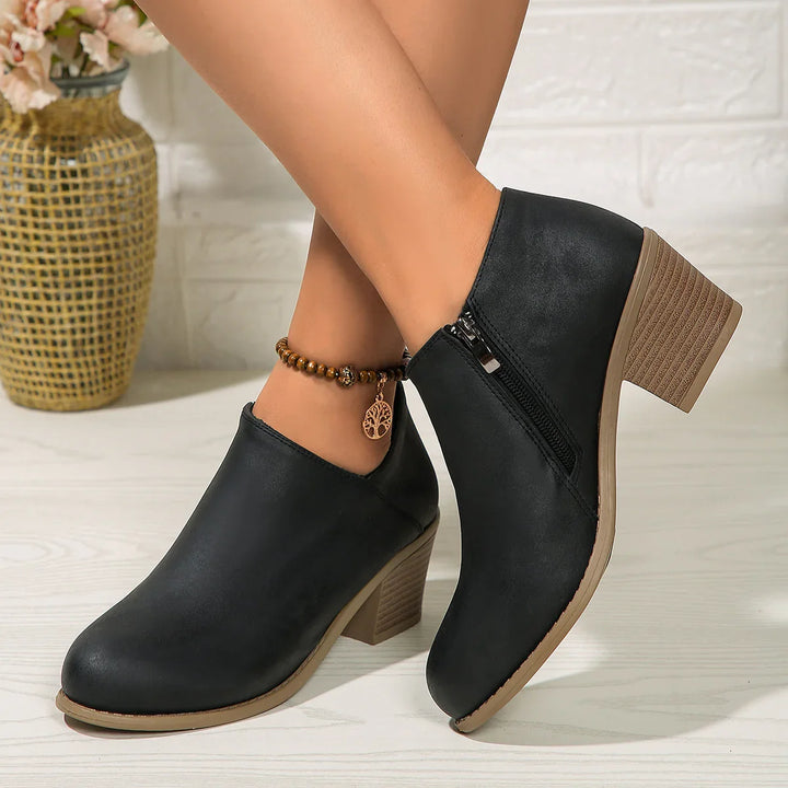 Black leather ankle boots with chunky heels and side zipper, worn with beaded ankle bracelet