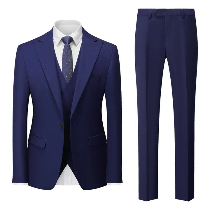 Men's navy blue three-piece suit with white dress shirt and patterned tie, featuring blazer, vest, and pants