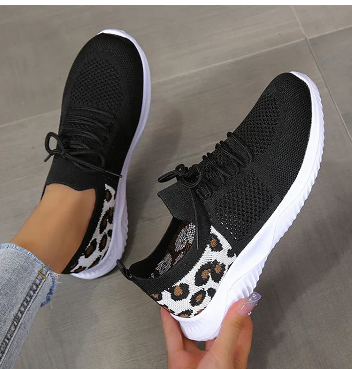 Black and white knitted sneakers with leopard print accents and white sole worn with jeans