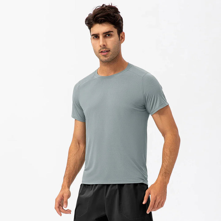 Man wearing light gray athletic t-shirt and black shorts on white background