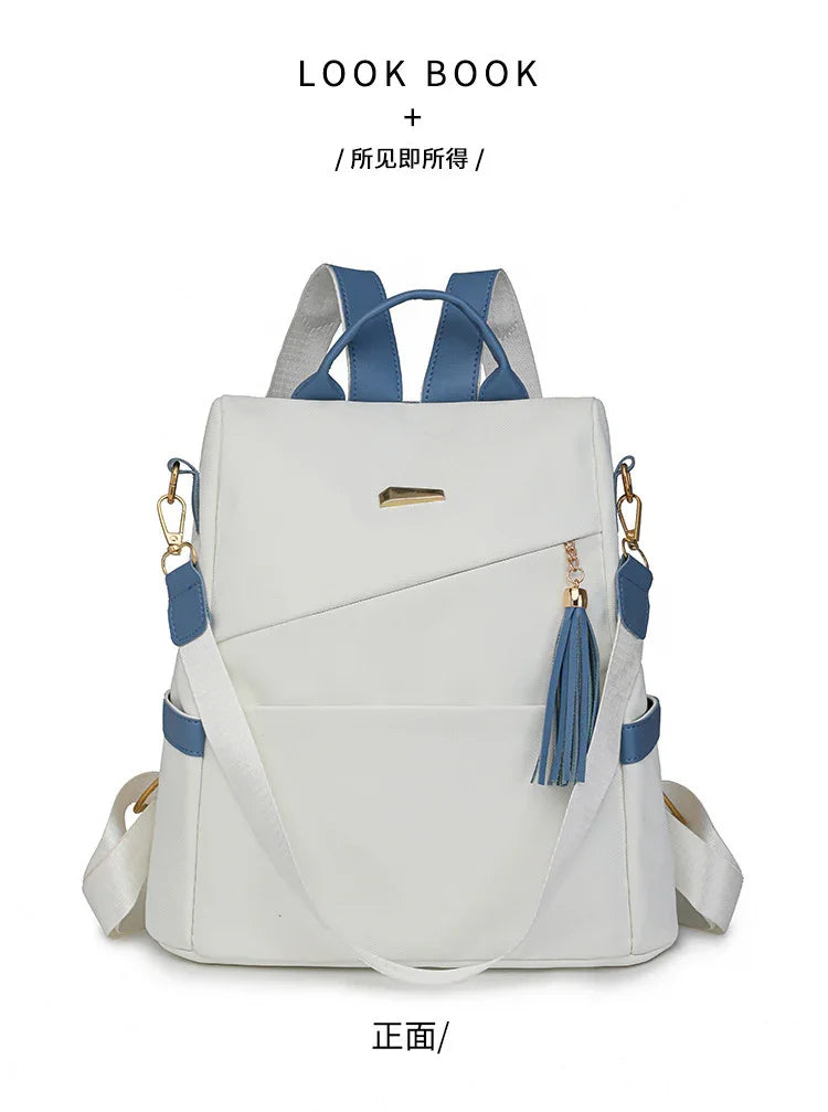 White backpack with blue straps and tassel charm, modern casual bag with gold accents