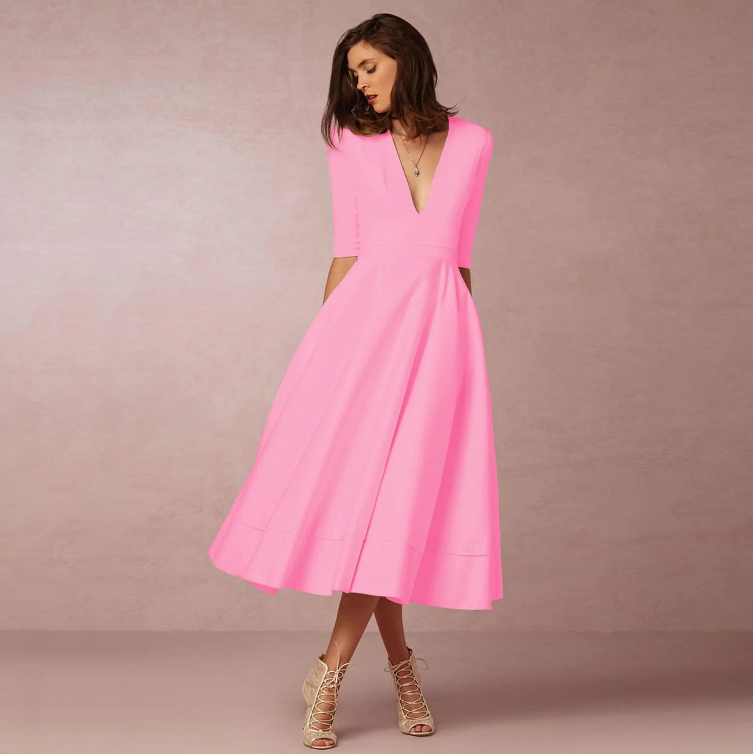 Woman in bright pink midi dress with deep V-neck and elbow sleeves, beige lace-up heels