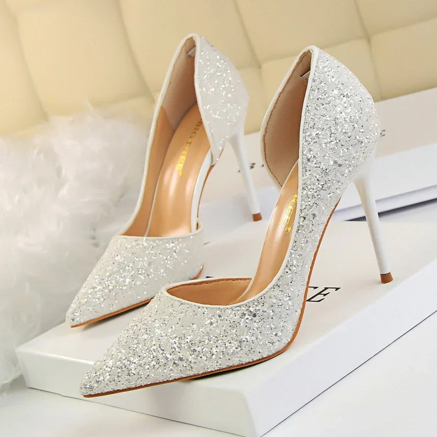 Pair of white glitter high heel stiletto shoes on white box with beige cushioned background