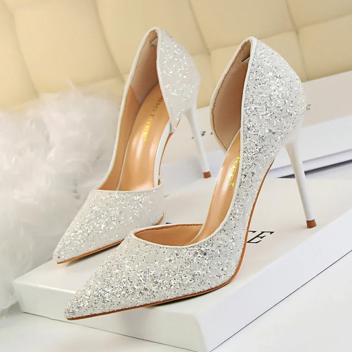 Pair of white glitter high heel stiletto shoes on white box with beige cushioned background