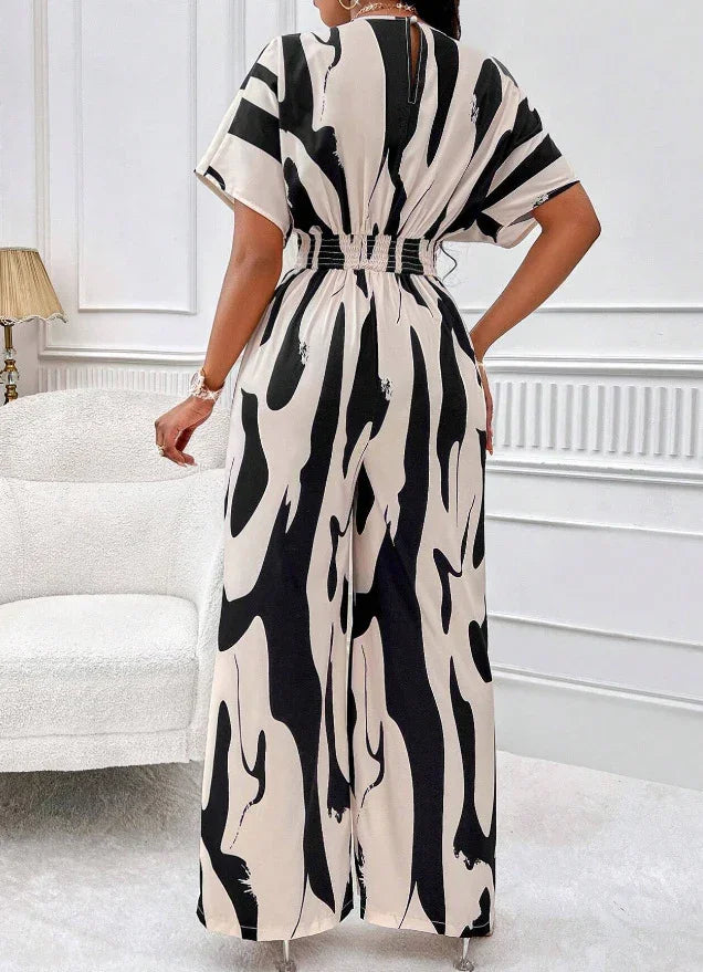 Back view of woman wearing black and white abstract print jumpsuit with wide legs in modern indoor setting