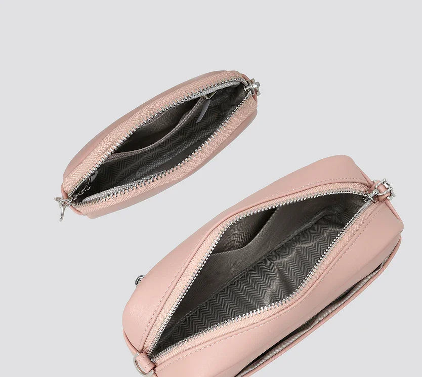 Two open light pink leather bags with silver zippers showing gray patterned fabric lining inside