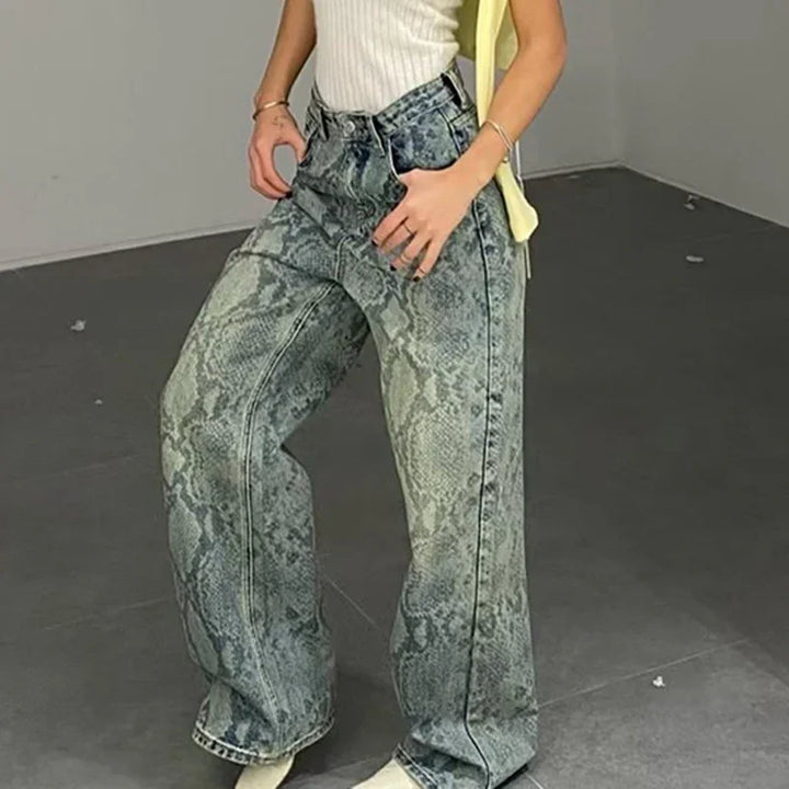 Woman wearing high-waisted gray snake print wide-leg jeans and white sleeveless top indoors